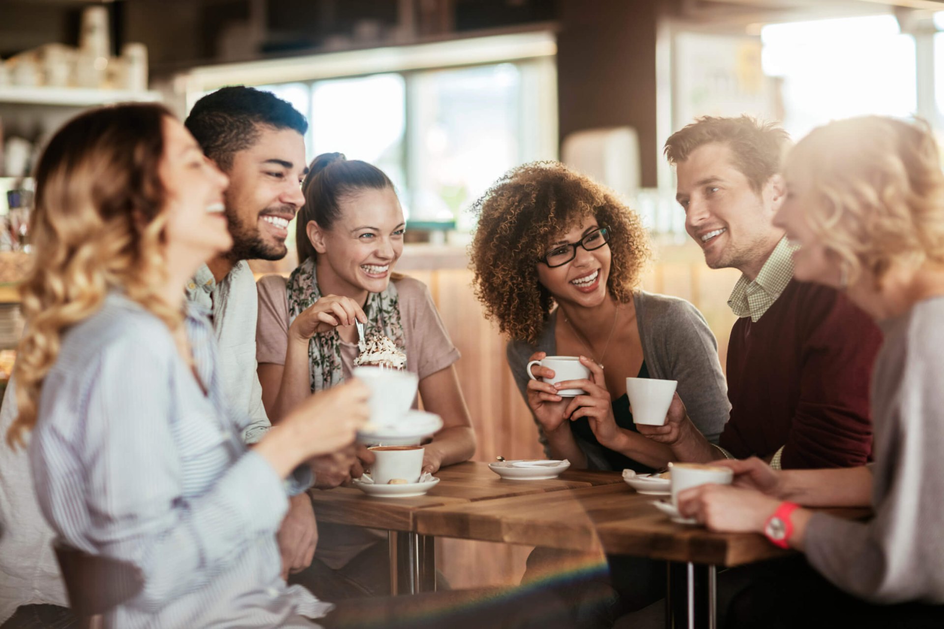 group of friends gathered drinking from mugs coffee shop near monument at pooler apartments